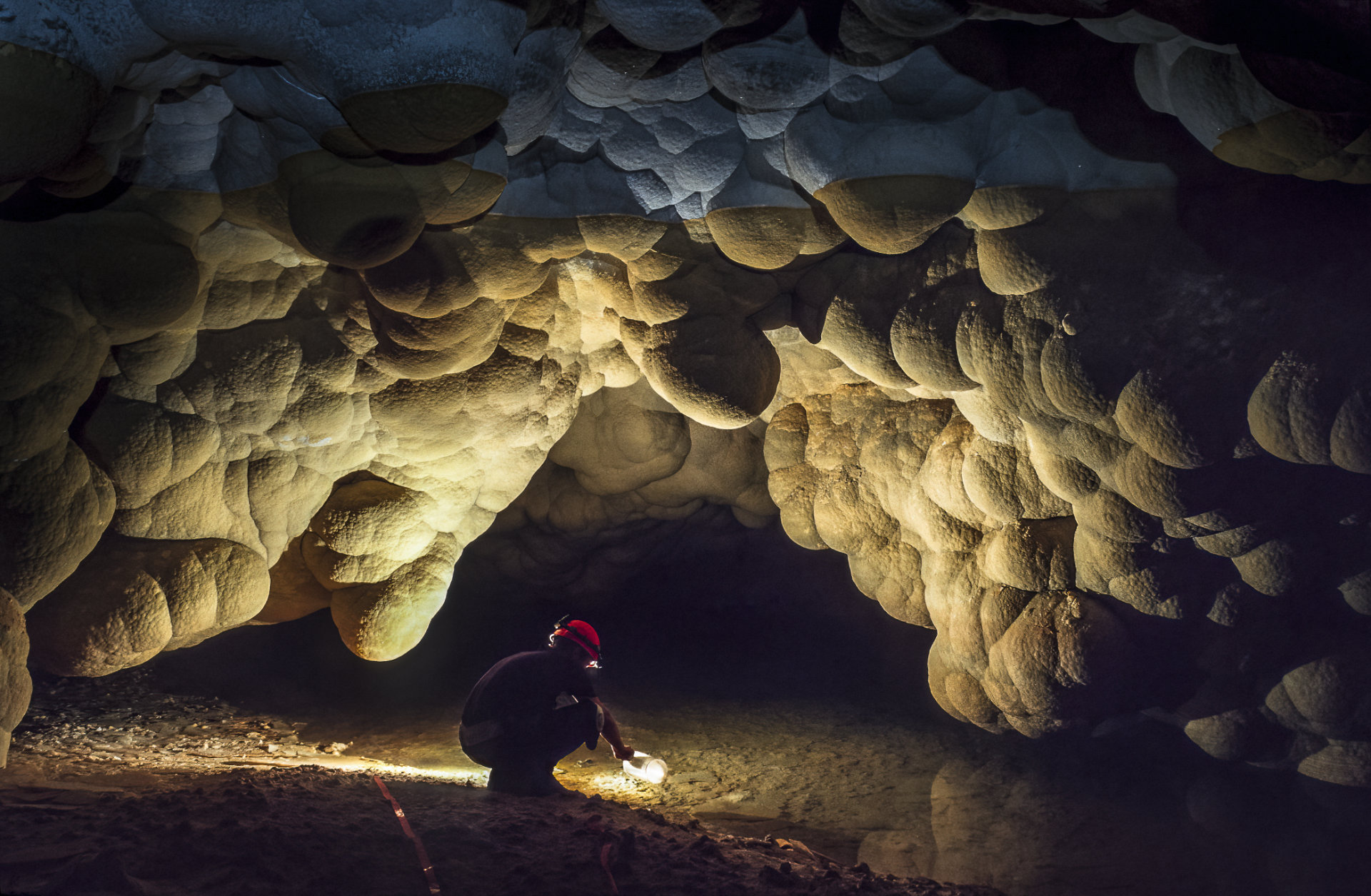 Umgeben von wolkenartigen Calcitformationen entnimmt ein Höhlenforscher  während einer einwöchigen Expedition wertvolles Trinkwasser aus dem Lake Louise.